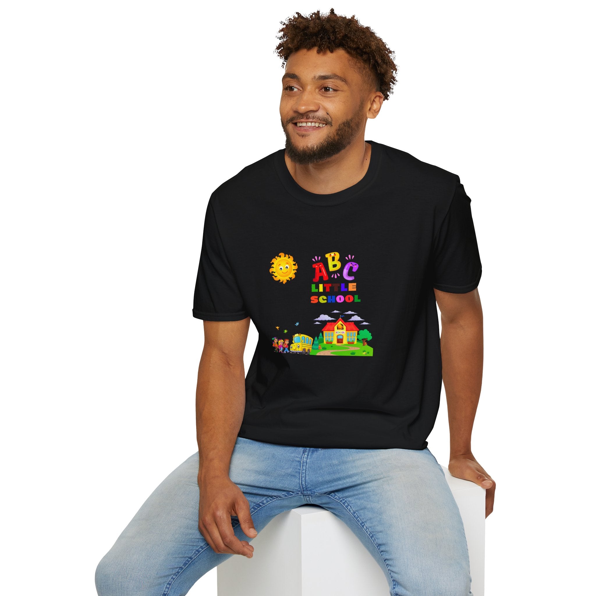Man wearing a black t-shirt with colorful graphics and text, sitting on a white stool against a white background.