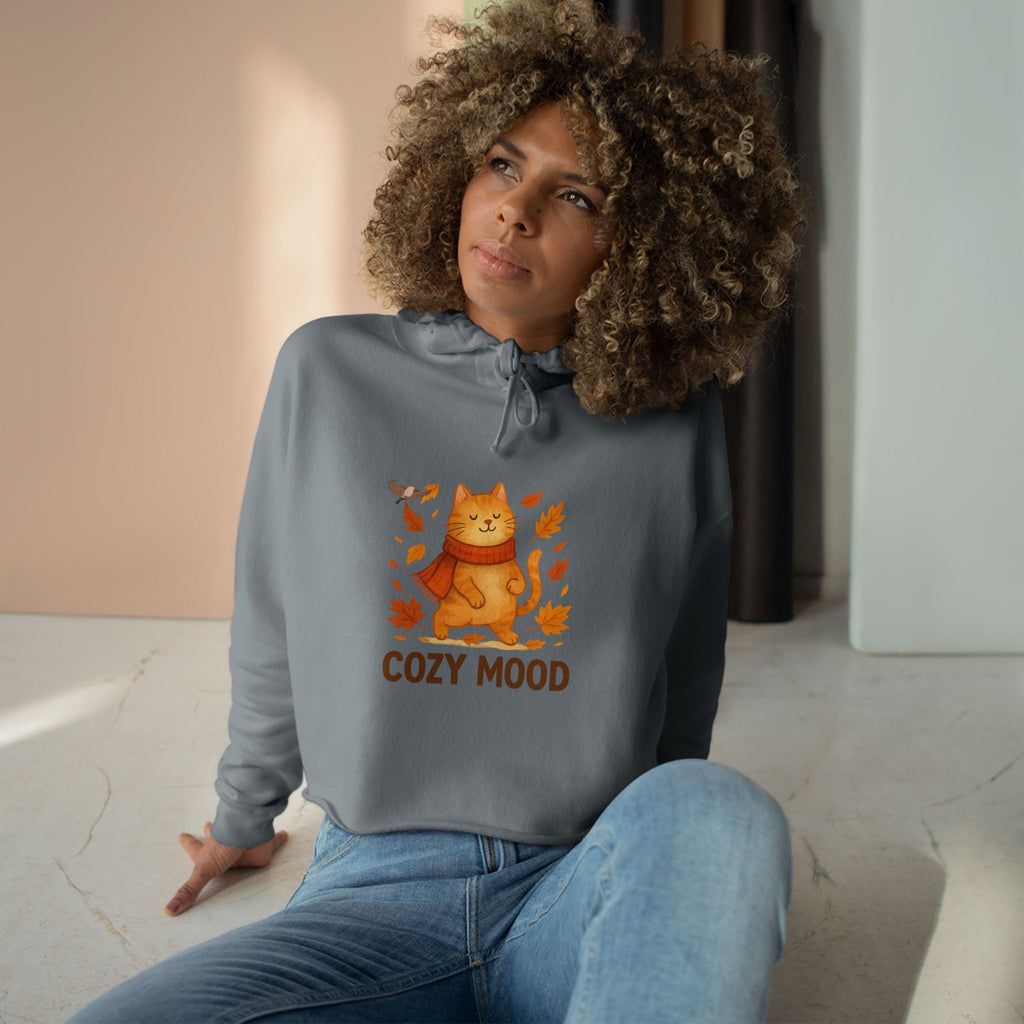 Woman wearing a gray sweatshirt with a cat graphic and 'Cozy Mood' text, sitting indoors.