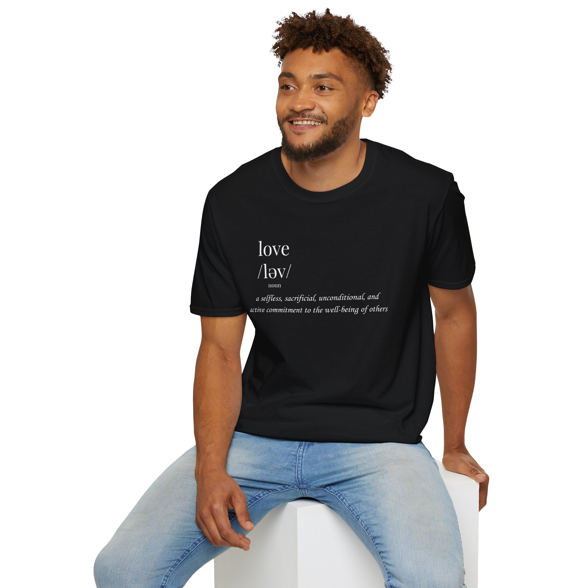 Man wearing a black t-shirt with text, sitting on a white stool against a white background