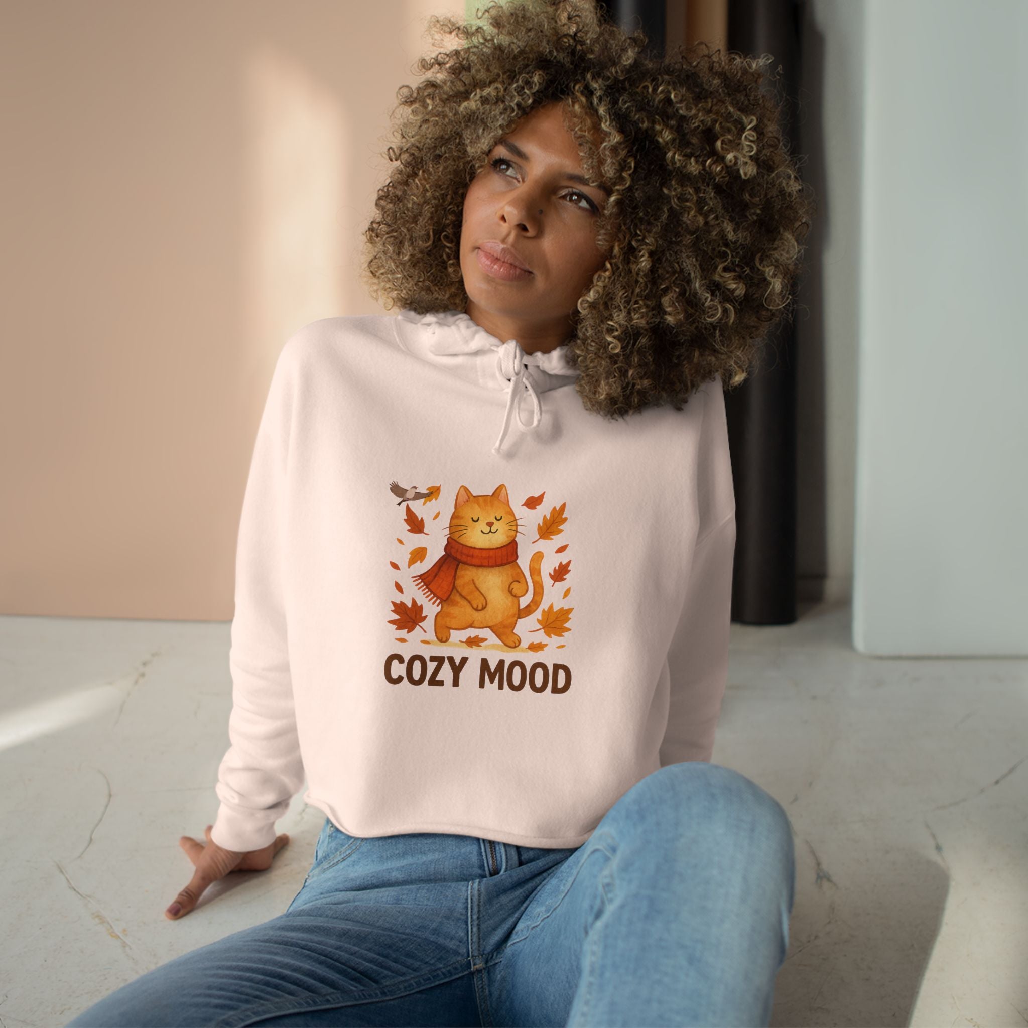 Person wearing a white hoodie with a cat graphic and 'Cozy Mood' text, sitting indoors.