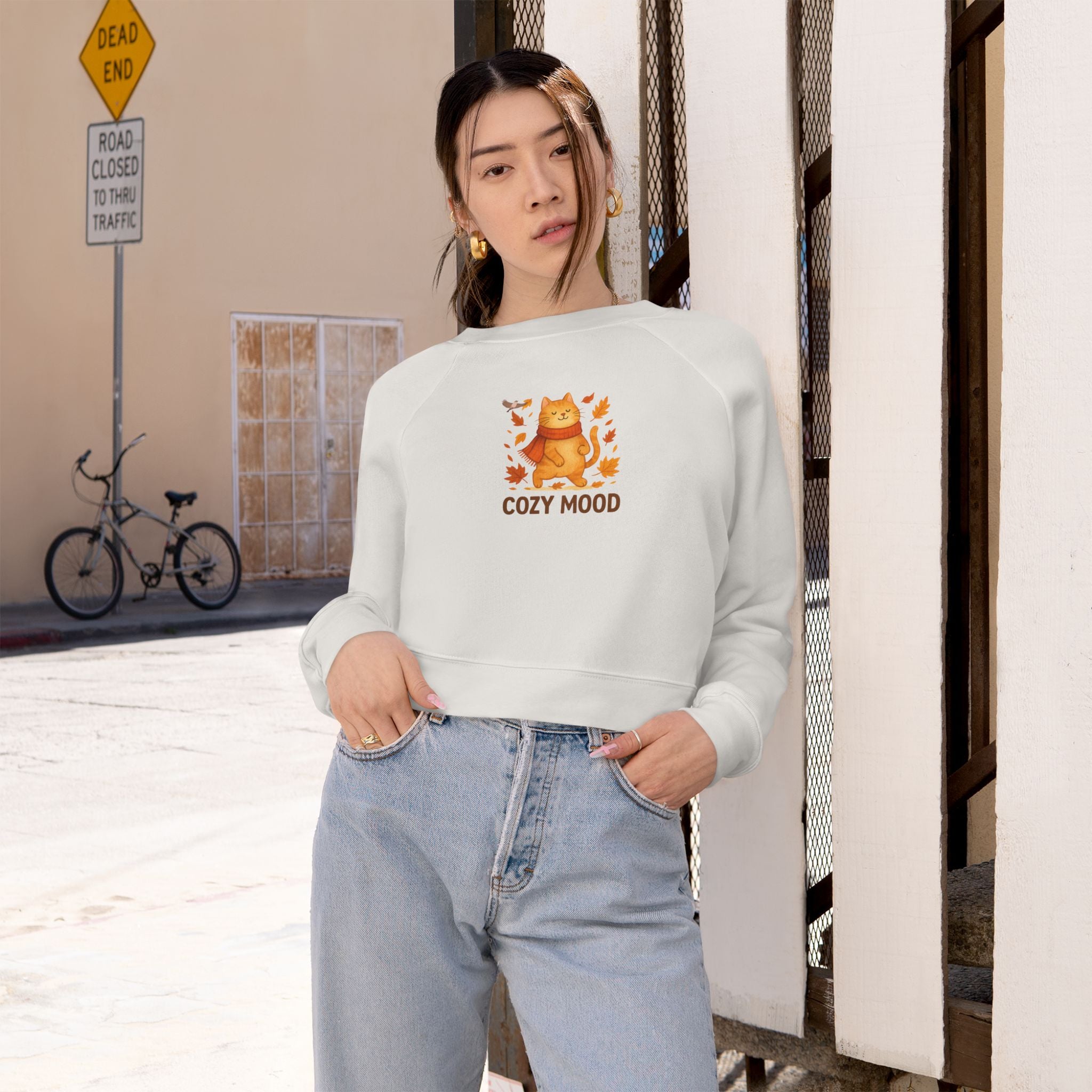 Person wearing a white sweatshirt with a graphic and text, standing in an urban setting.