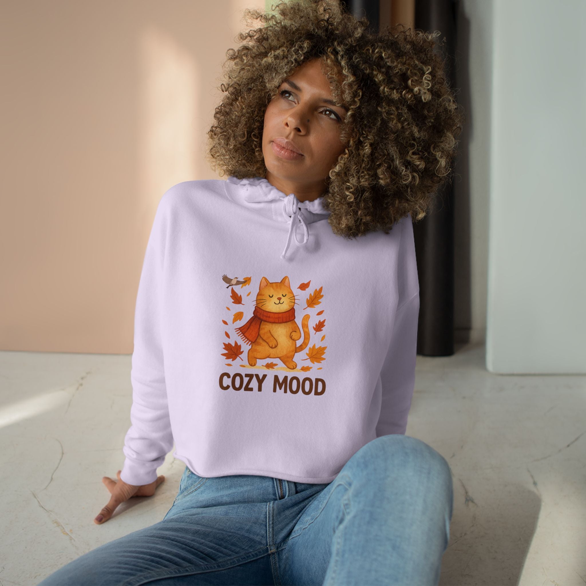 Person wearing a light purple hoodie with a cat graphic and 'Cozy Mood' text, sitting indoors.