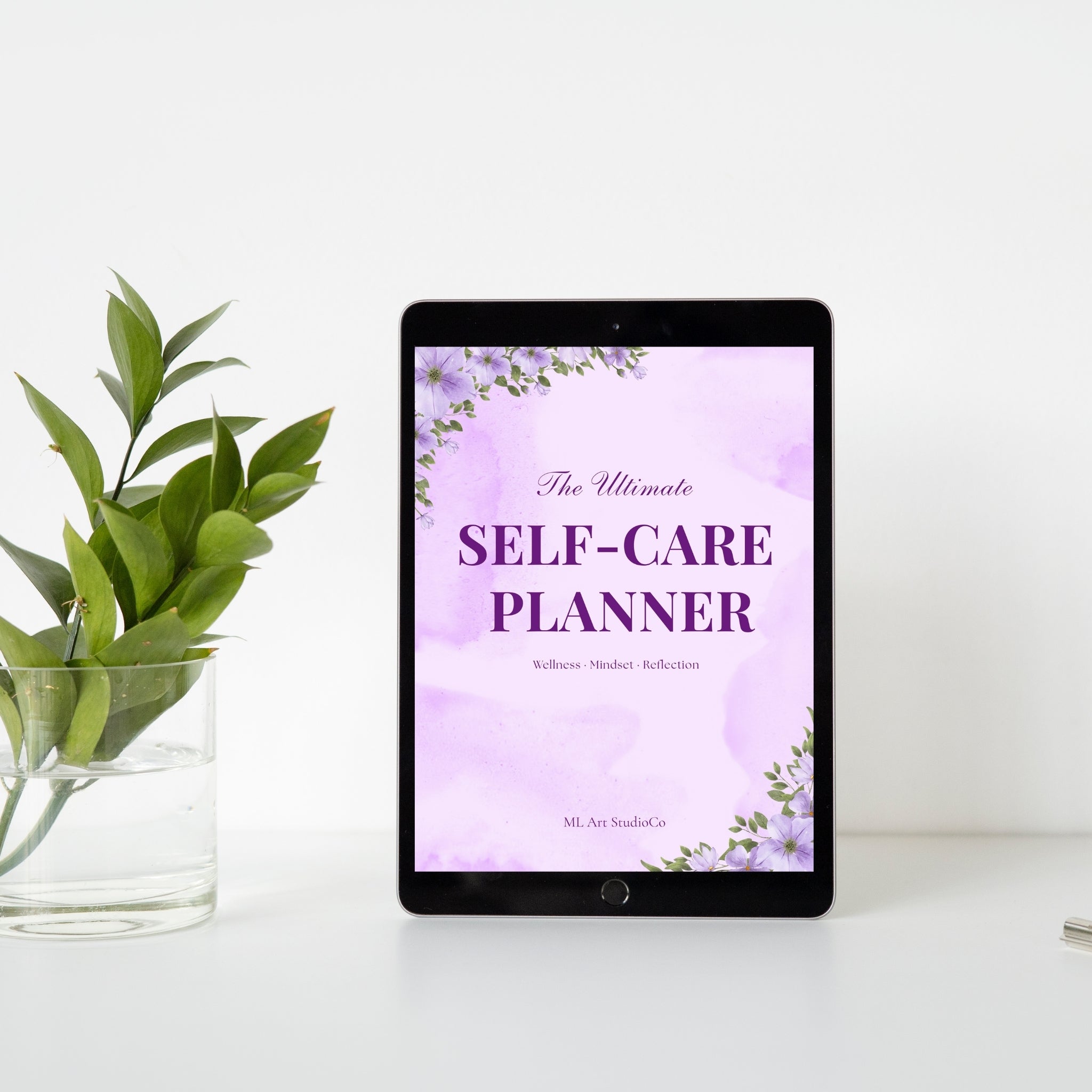 Tablet displaying 'The Ultimate Self-Care Planner' on a white surface with a plant.