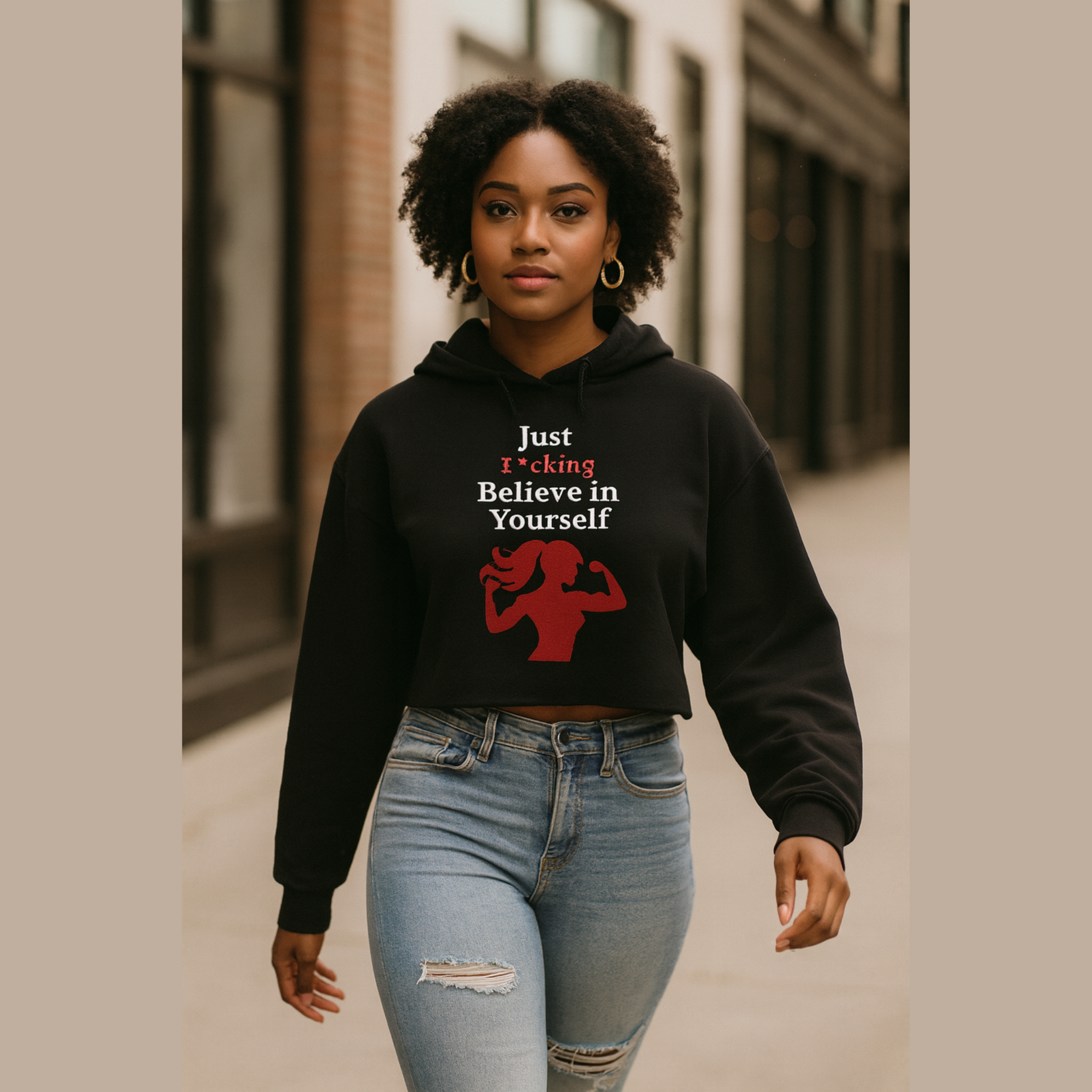 Person wearing a black hoodie with motivational text and graphic, standing on a street.